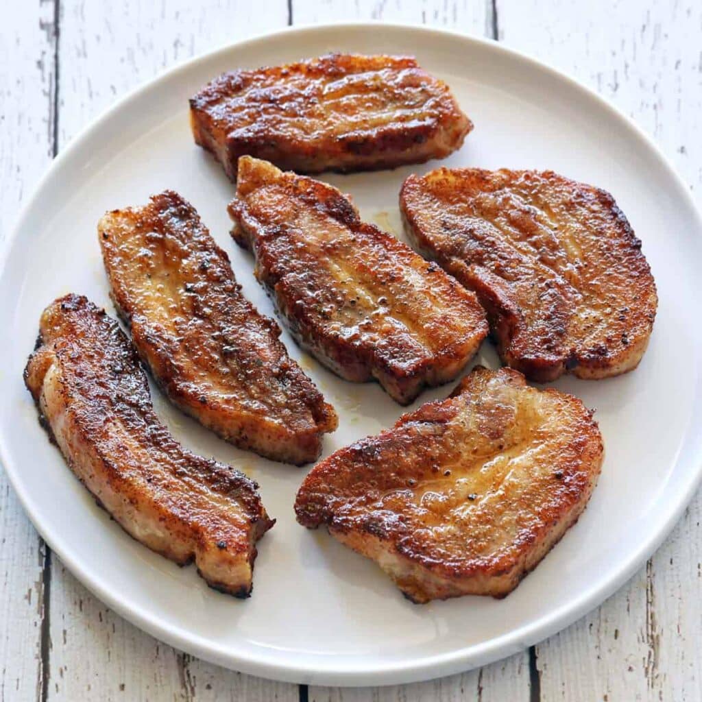 A top view of pork belly strips rosted inisde a plate