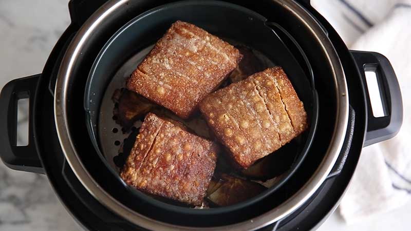 A view of a pork belly being roated in an air fryer