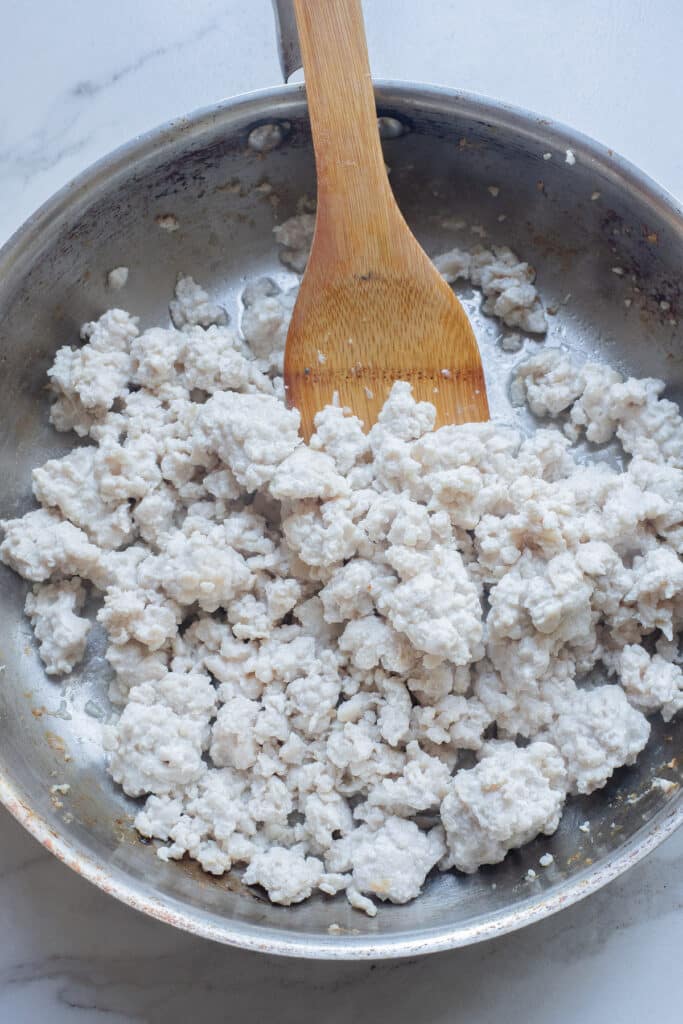 A view of ground turkey being stired inside a pan