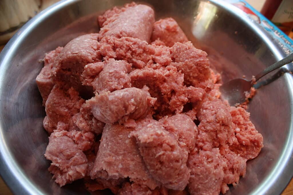 A view of thick raw pink ground meat inside a pan