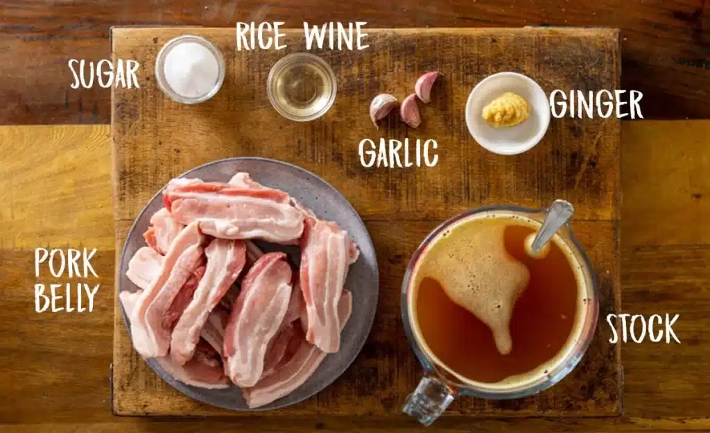 An overhead view of pork belly ingredients with sugar ginger rice wine stock and garlic