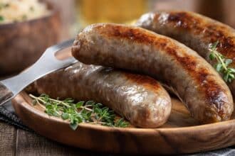 Closeup Of Fried Bratwurst Garnished With Thyme On A Plate