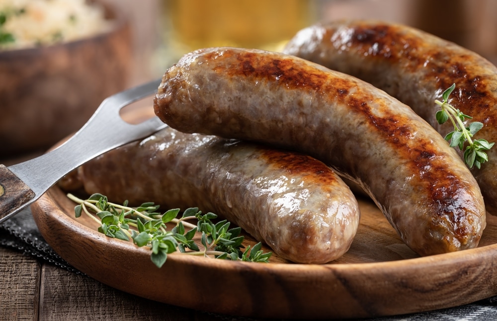 Closeup Of Fried Bratwurst Garnished With Thyme On A Plate