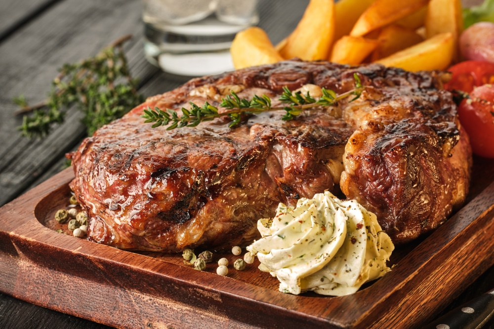 Ribeye steak with potatoes onions and baked cherry tomatoes Juicy steak with flavored butter