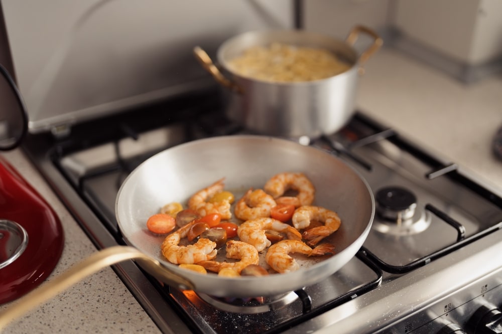 Shrimp Being Sauteed With Tomatoes In A Modern Kitchen Setting