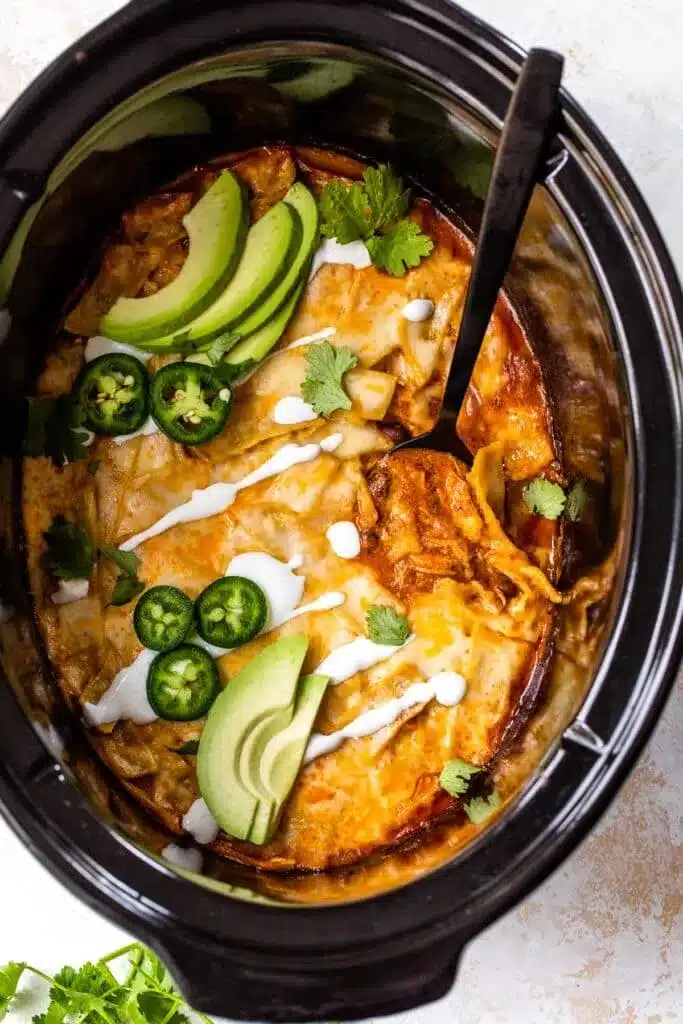 Slow Cooker Chicken Enchiladas garnished with green chillies and cilantro