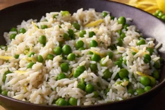 a bowl of rice cooked in chiken broth with peas