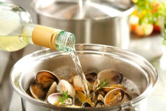 pouring white wine in cooking sea food