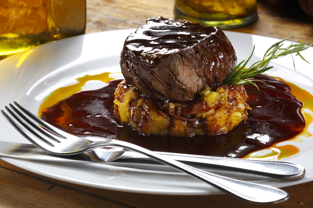 Filet Mignon in a plate with sauces and spoon and fork