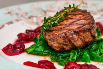 Filet mignon Grilled beef steak minion with with spinach and cherry sauce on a patterned plate