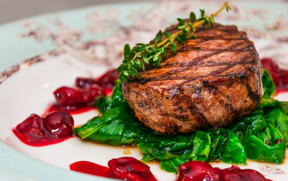 Filet mignon Grilled beef steak minion with with spinach and cherry sauce on a patterned plate