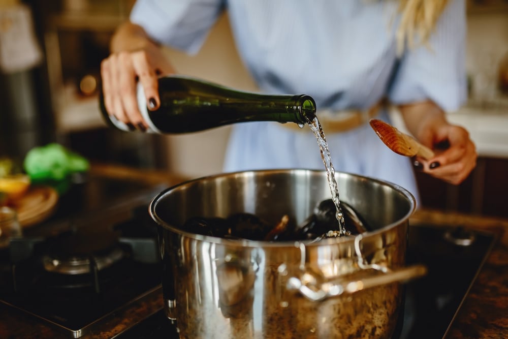 Girl Adding White Wine To A Pan With Mussels Woman