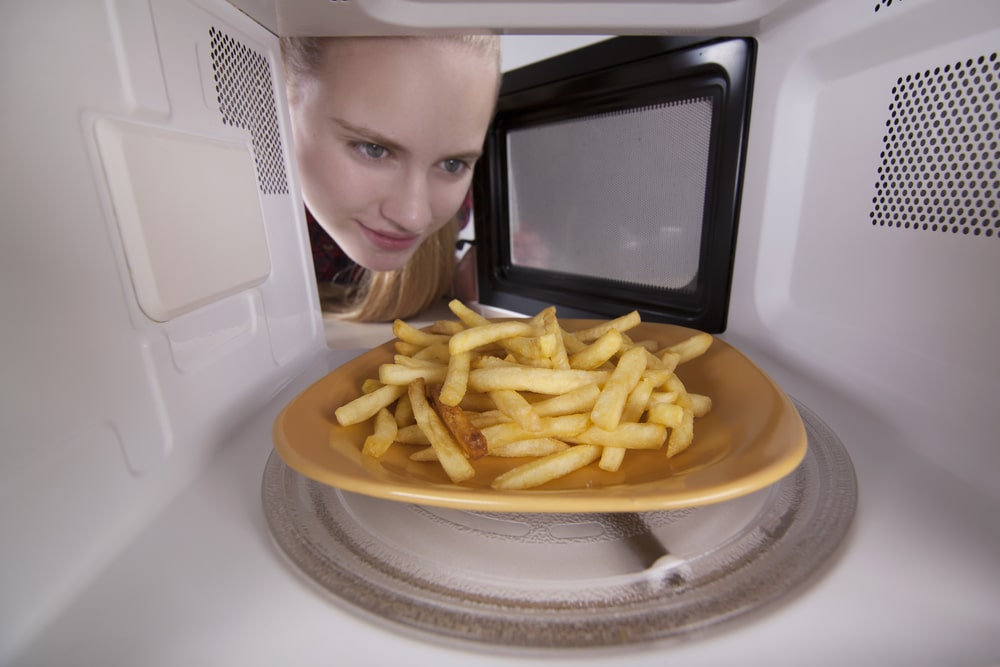 Girl Opens The Door Microwave Looking Inside Waiting For Warm