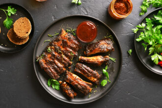 Grilled Spare Ribs On Plate Over Black Stone Background Top