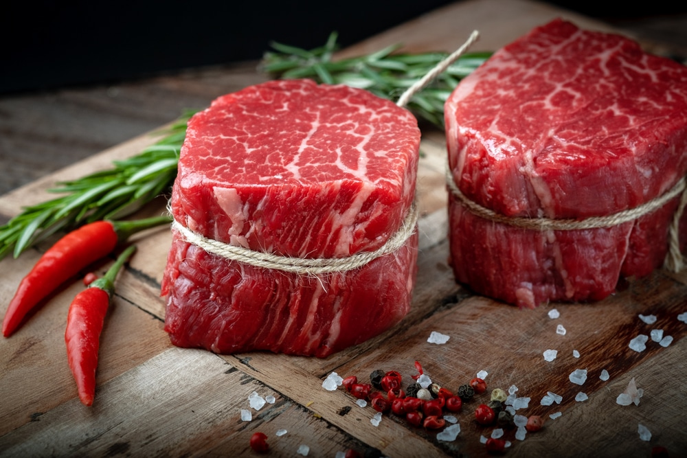 Raw beef filet Mignon steak on a wooden Board with pepper and salt black Angus marbled meat