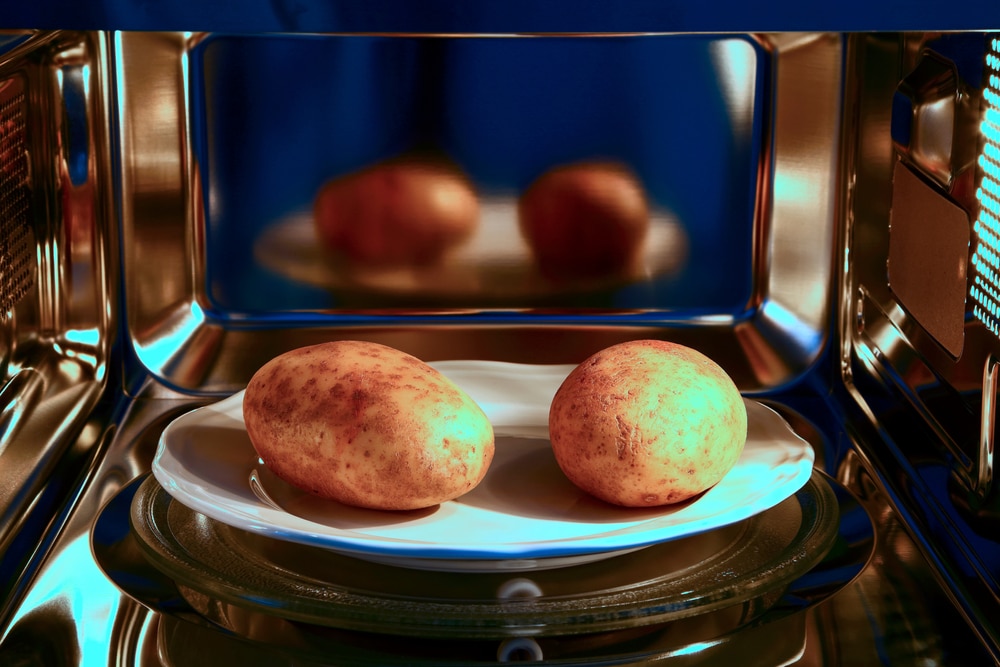 Two Baked Potatoes Ready To Cook In A Microwave Oven