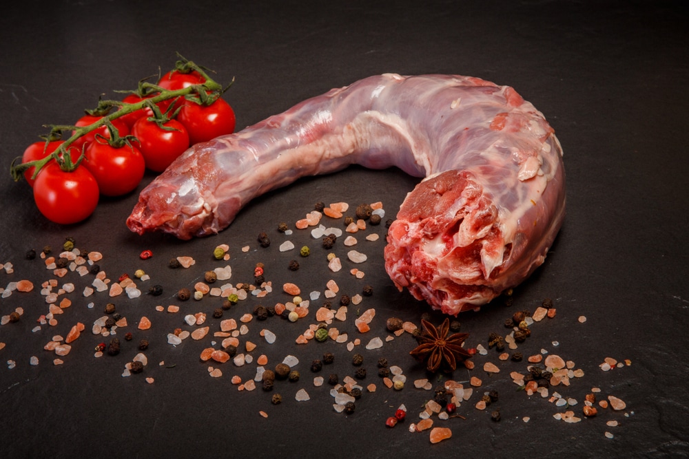 top view closeup raw turkey neck without skin served with assorted spices and tomatoes cherry on black background