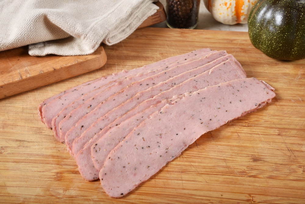 Slices of raw uncured turkey bacon on a wooden cutting board