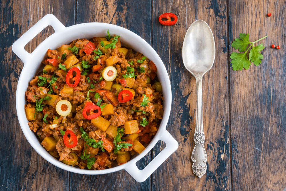 Picadillo a stew of ground beef and tomatoes with raisins and olives in a white casserole