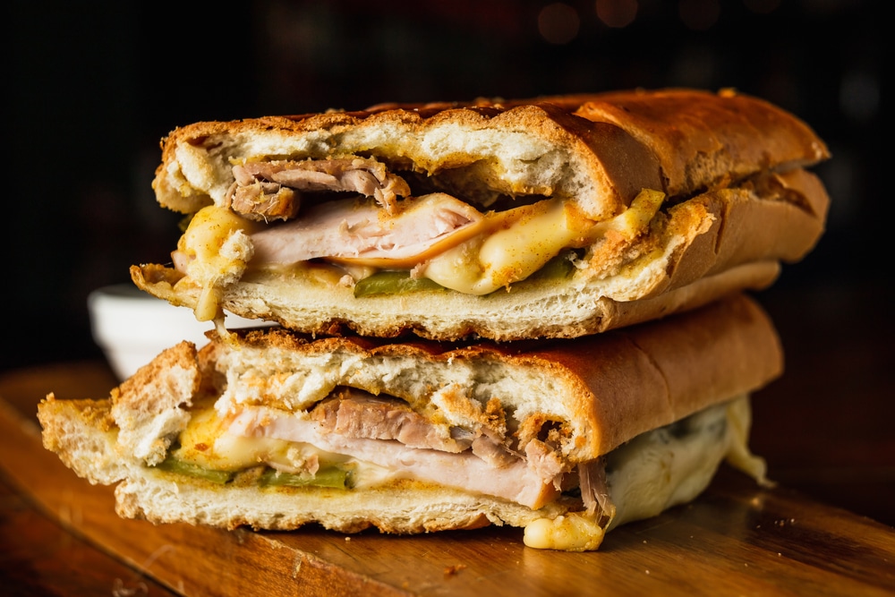 Traditional cuban sandwich with cheese ham and fried pork served on a wooden board